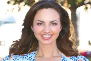 Orange City Council candidate Brandy Romero smiling outdoors in a blue floral top.