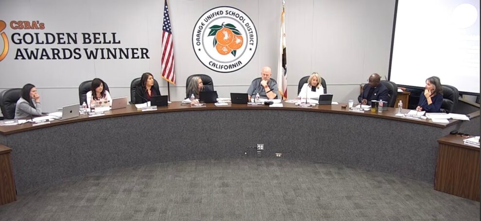 Orange Unified School District Board of Education members seated at the dais during the October 15, 2026 board meeting, with the district seal and a Golden Bell Awards banner behind them.
